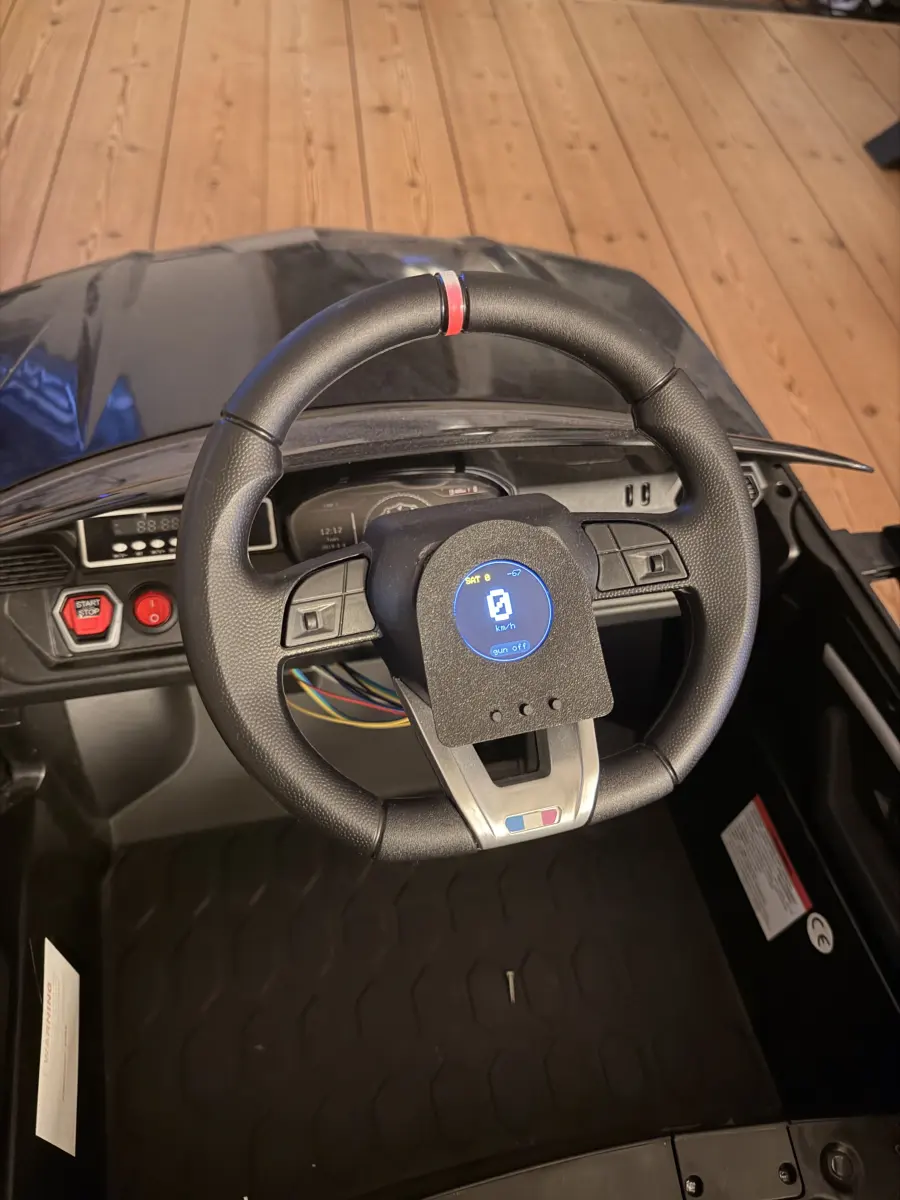 The round display in the steering wheel hub, showing speed, satellite count and gun state
